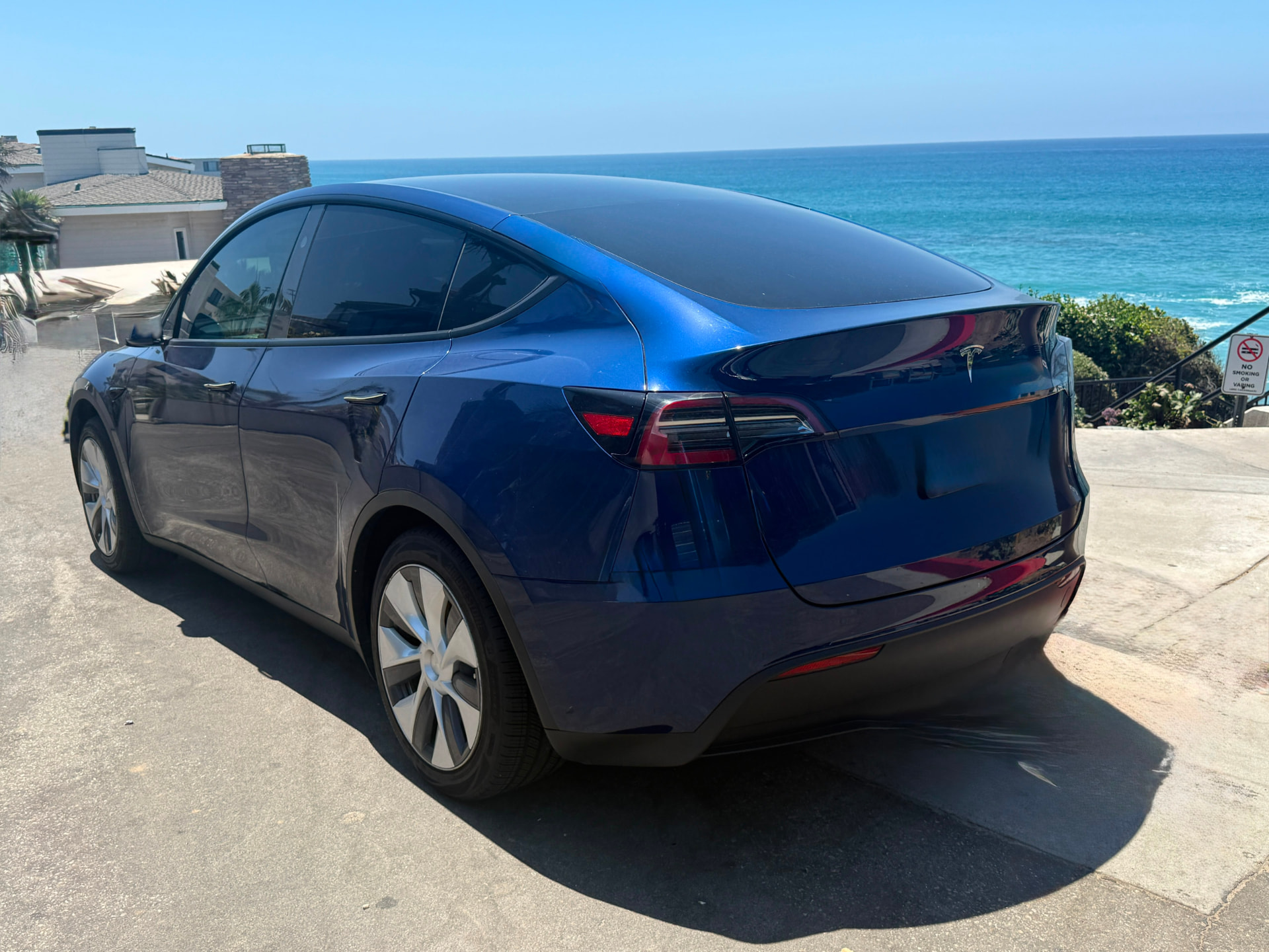 Blue Tesla Model Y parked above the ocean in Laguna Beach