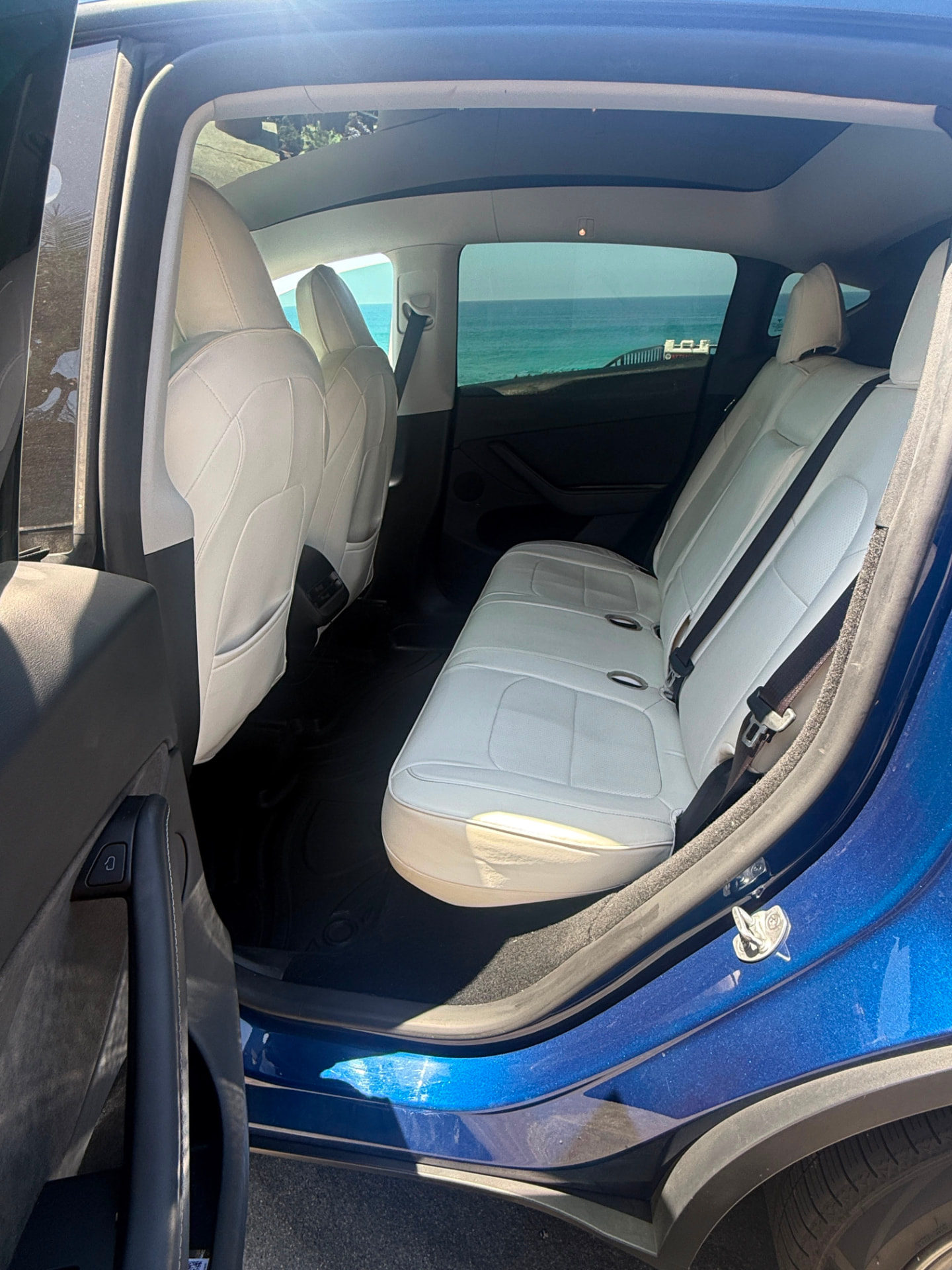 Rear passenger seats in white leather with an ocean view
